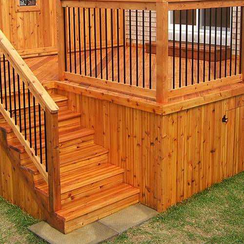 Cedar deck staining Toronto in progress with a brush and stain can on the boards.