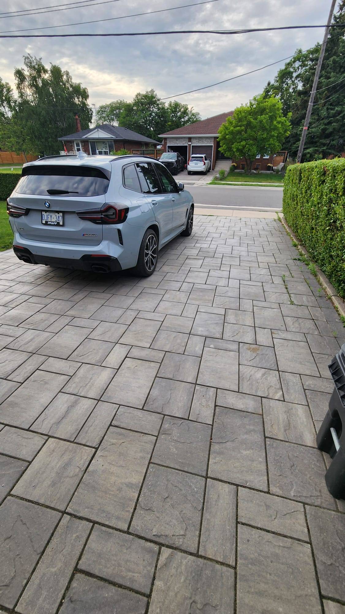 Crew applying interlock sealing Scarborough driveway with sprayer, stones evenly coated.